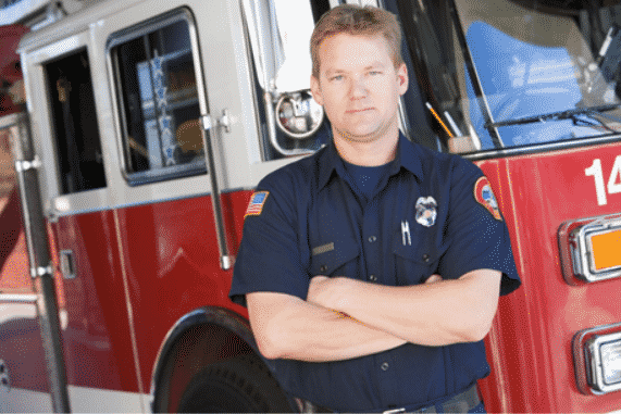 Firefighter in blue uniform standing in front of a fire truck