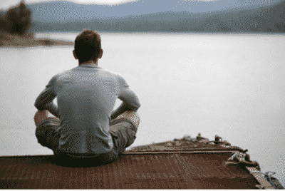 Man in recovery sitting on a dock looking at a lake
