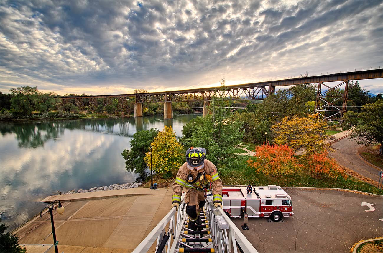 Fire fighter walking up a long ladder on the scene