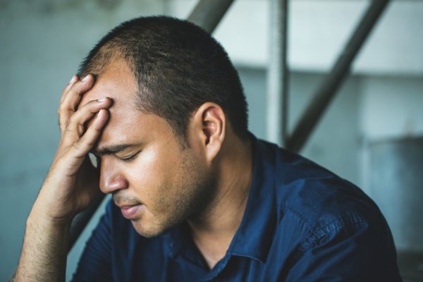 Fire fighter struggling with alcohol abuse sitting down with his hand on his head