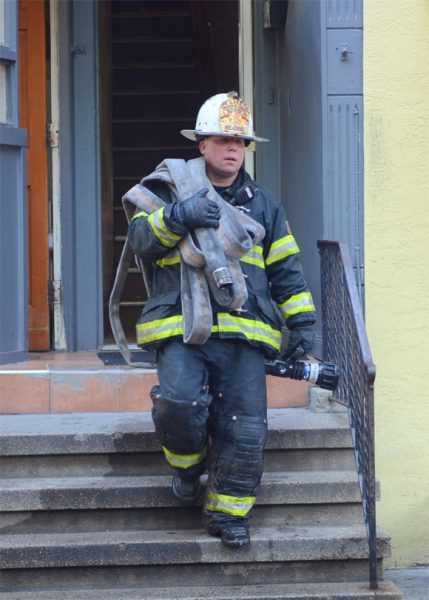 Fire fighter carrying a fire hose down stairs