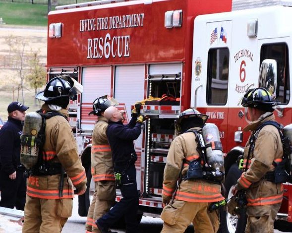 A group of fire fighters surrounding the side of a fire truck