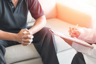 Man struggling with PTSD in a therapy session sitting across from the therapist