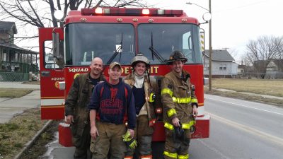 Fire fighters in uniform standing in front of a fire truck