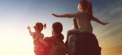 A family with two children looking into the sunset with hope for a new day. 