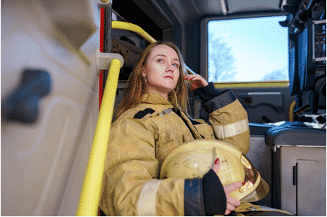 Female fire fighter sitting in the back of a fire truck deep in thought