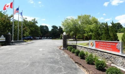 COE main entrance sign with flags flowing on flagpoles