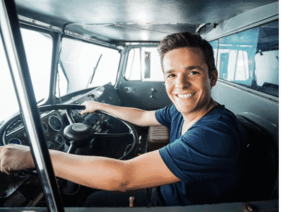 Fire fighter smiling with his hands on the wheel of a fire truck