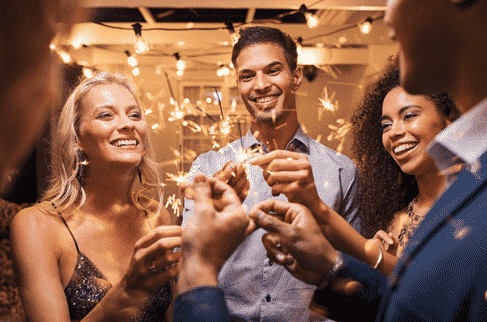 Group of people in recovery holding sparklers at a holiday party