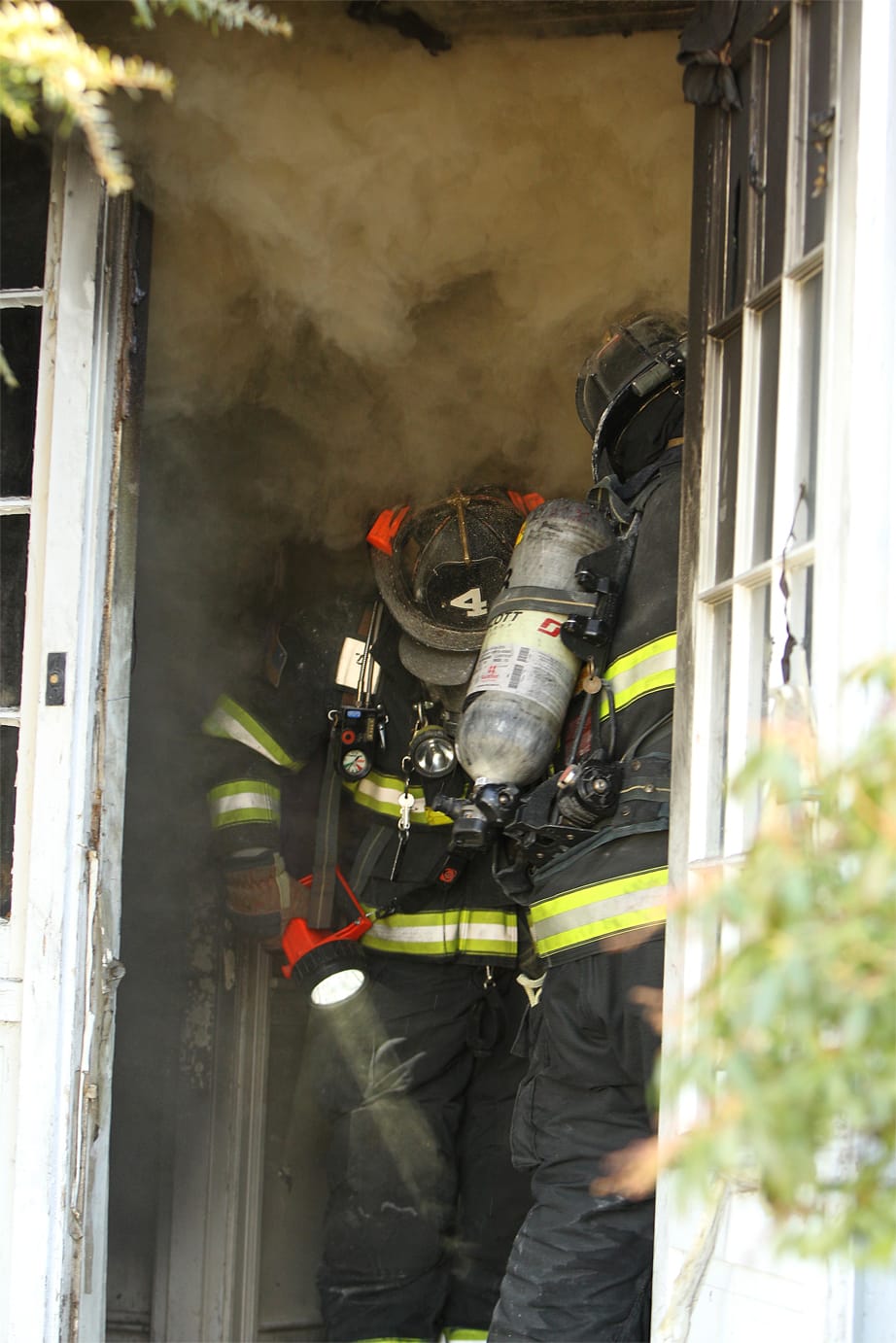 Fire fighter shining a flashlight on the ground surrounded by smoke