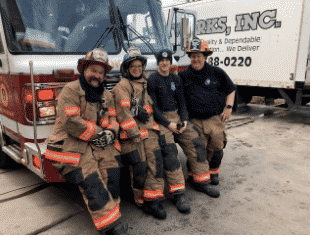 Bill Allenbaugh with his fellow crew members leaning against the front of the fire truck