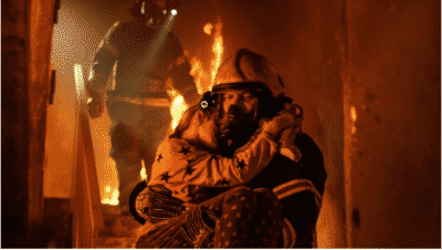Fire fighter carrying a young girl down the stairs from a burning house