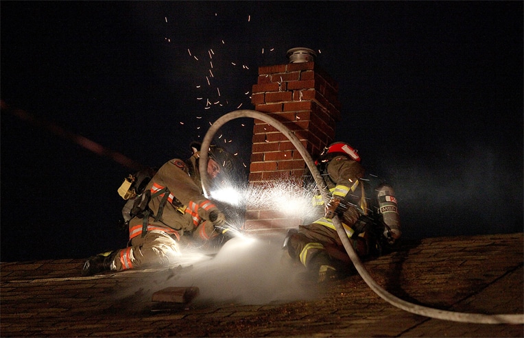 Two fire fighters putting out a fire on a roof