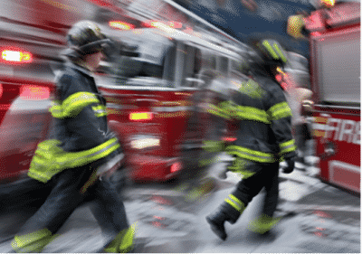 A blurry image of a group of fire fighters walking between fire trucks