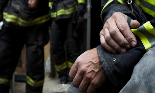 Fire fighter holding his arm sitting away from his fellow crew members